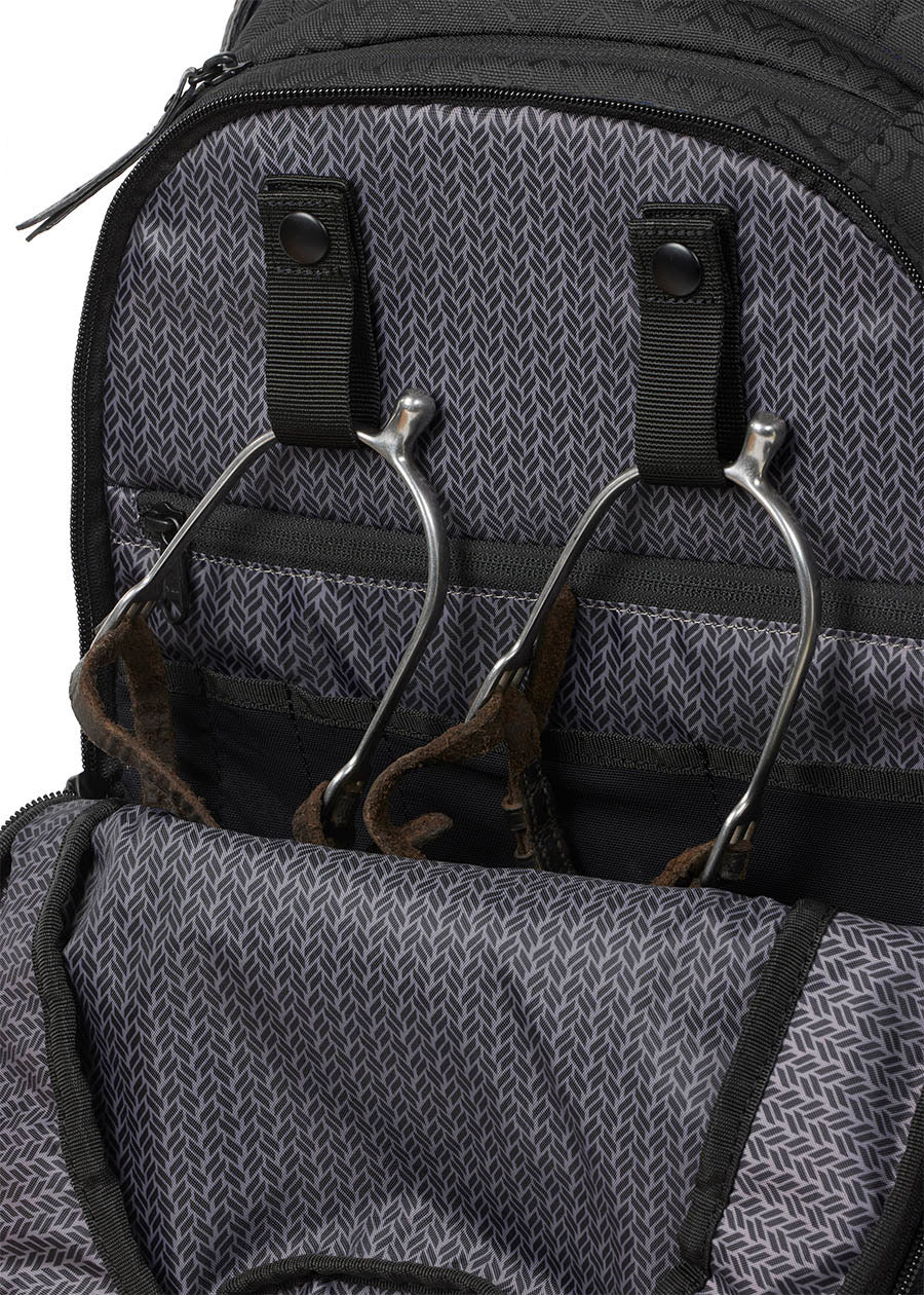 Detailed view of the Kerrits EQ Backpack fabric, highlighting its interior snap spur straps to keep your riding essentials tidy.