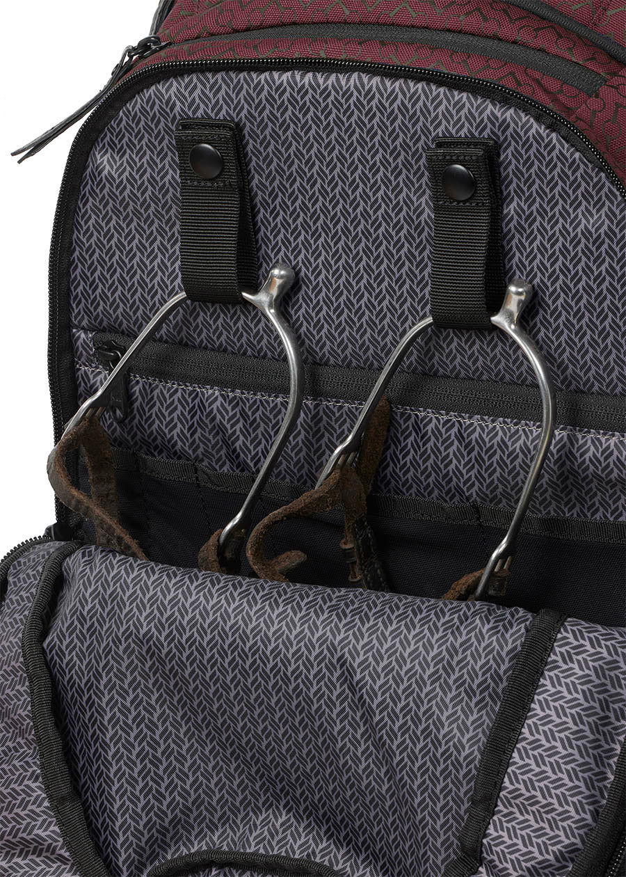 Detailed view of the Kerrits EQ Backpack fabric in Burgundy, highlighting its interior snap spur straps to keep your riding essentials tidy.