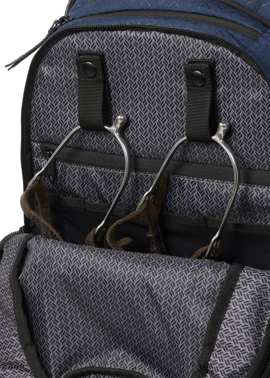 Detailed view of the Kerrits EQ Backpack fabric in Navy, highlighting its interior snap spur straps to keep your riding essentials tidy.