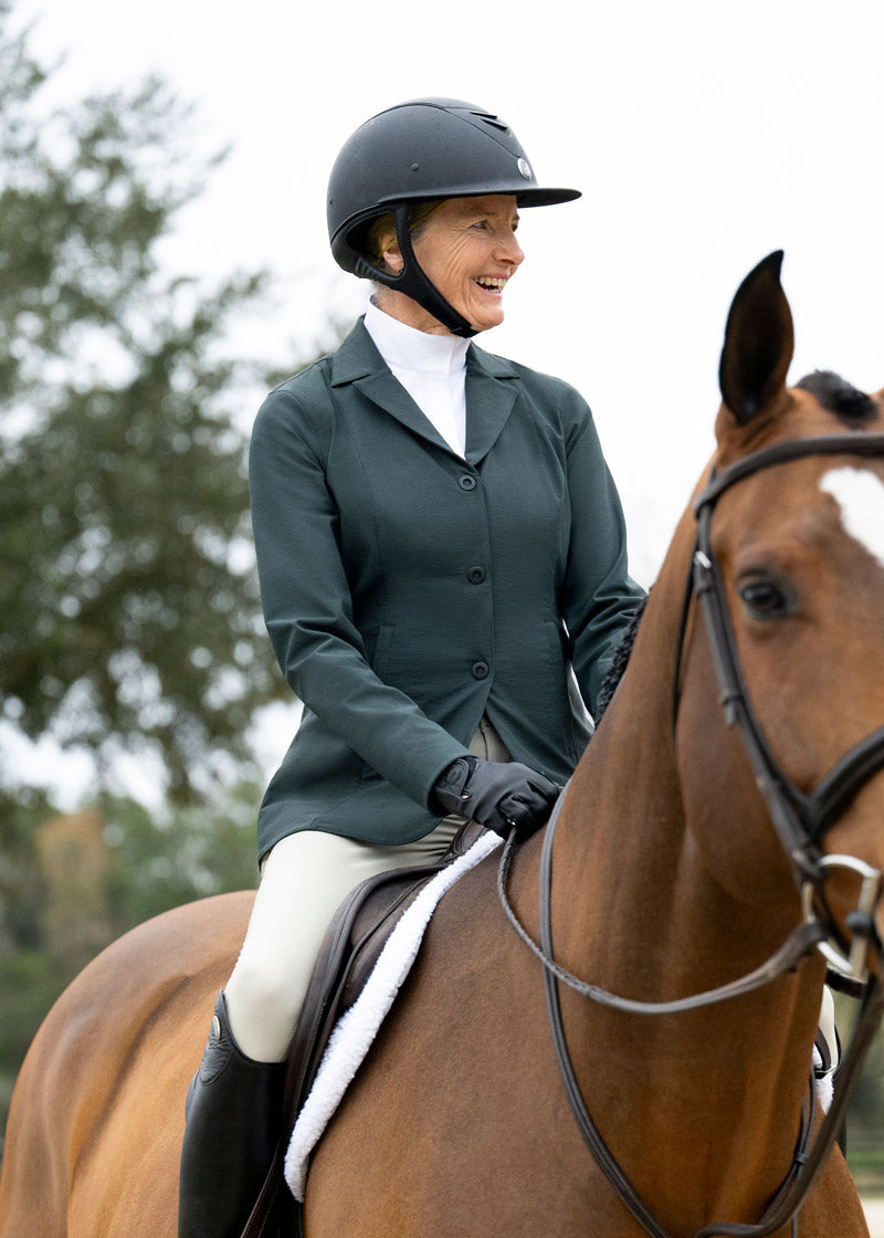 Equestrian wearing the Stretch Competitor Koat while riding, demonstrating the coat's flexibility and elegant appearance in the saddle