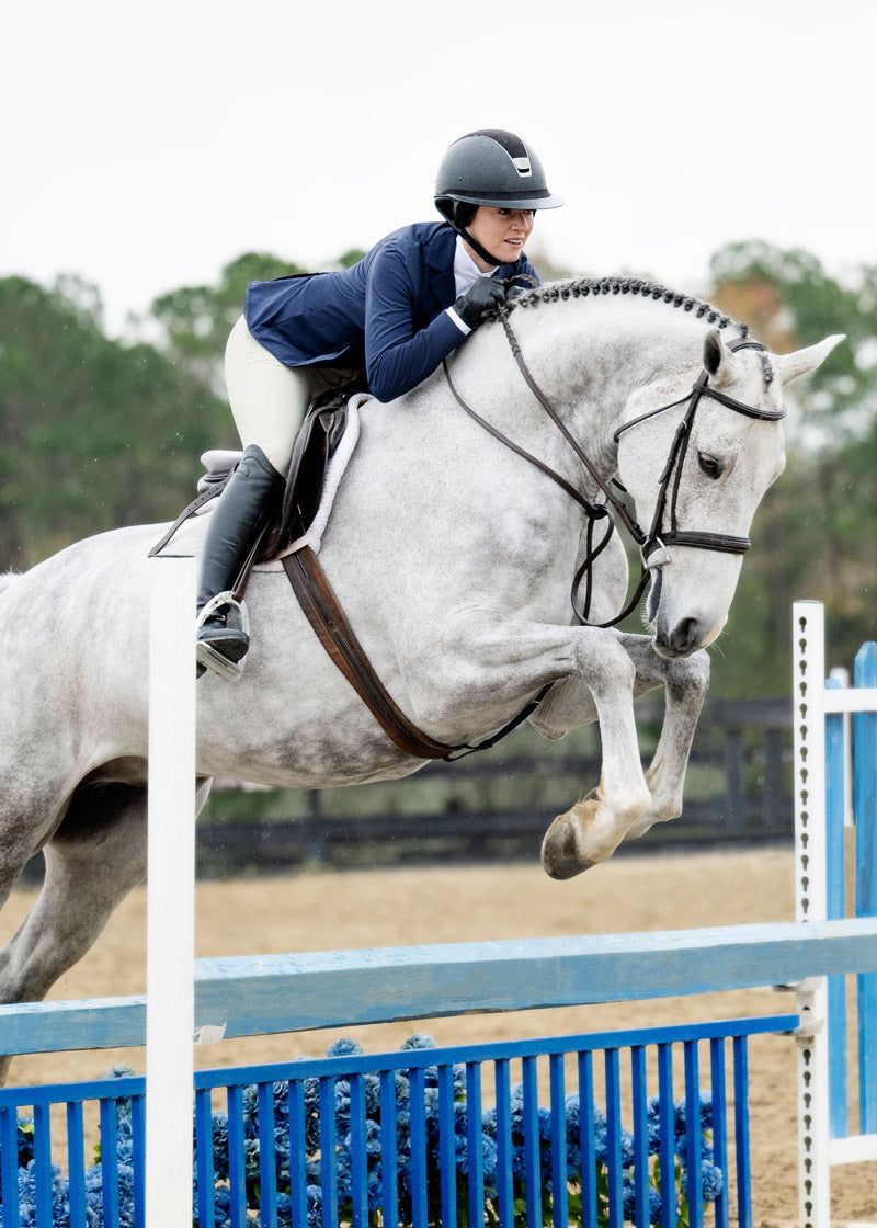 Equestrian wearing the Stretch Competitor Koat while riding, demonstrating the coat's flexibility and elegant appearance in the saddle