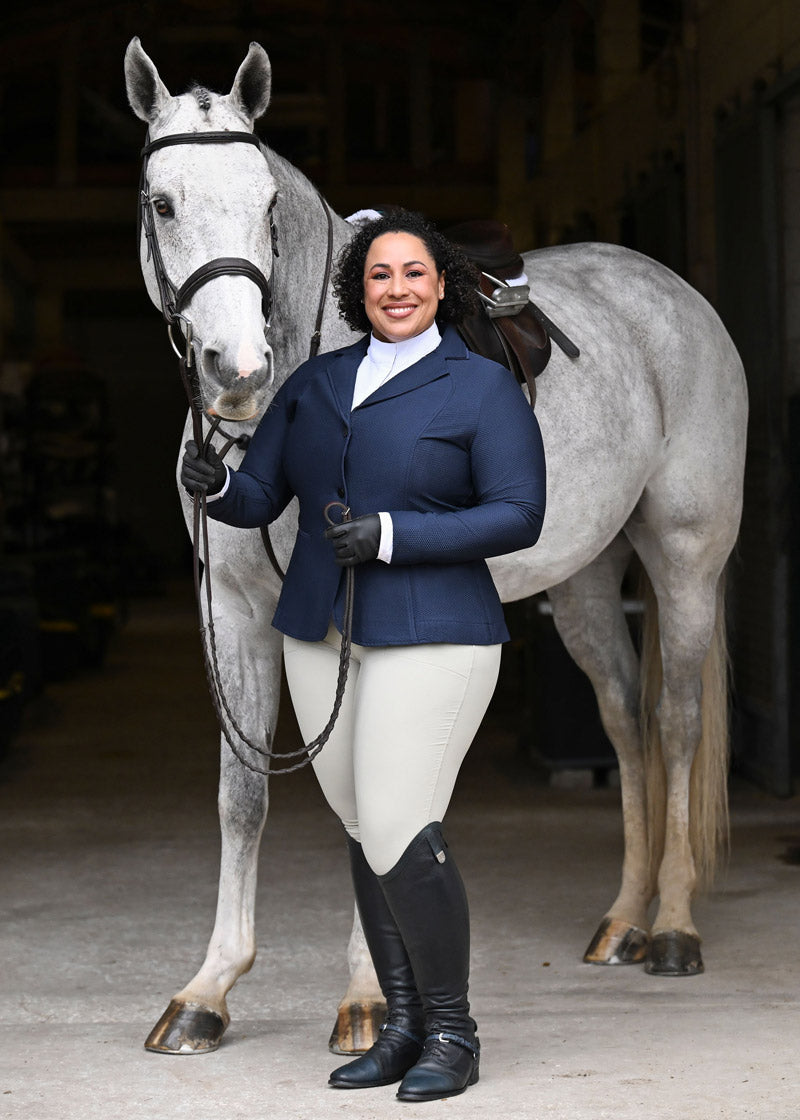 Equestrian wearing the Crossover II Knee Patch Breech in Sand with a navy show coat and white show shirt for a complete competition look.