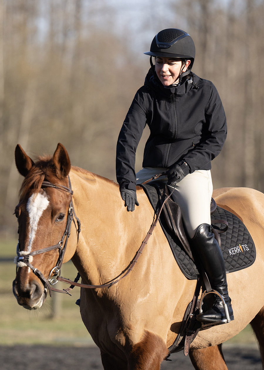 Equestrian wearing the Waterproof All Around Rain Jacket while riding, demonstrating its functionality and freedom of movement