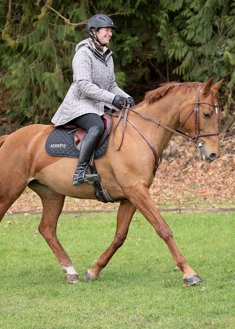 Rider performing barn chores in the Elevation Insulated Winter Equestrian Jacket, showcasing durability and comfort during activities.