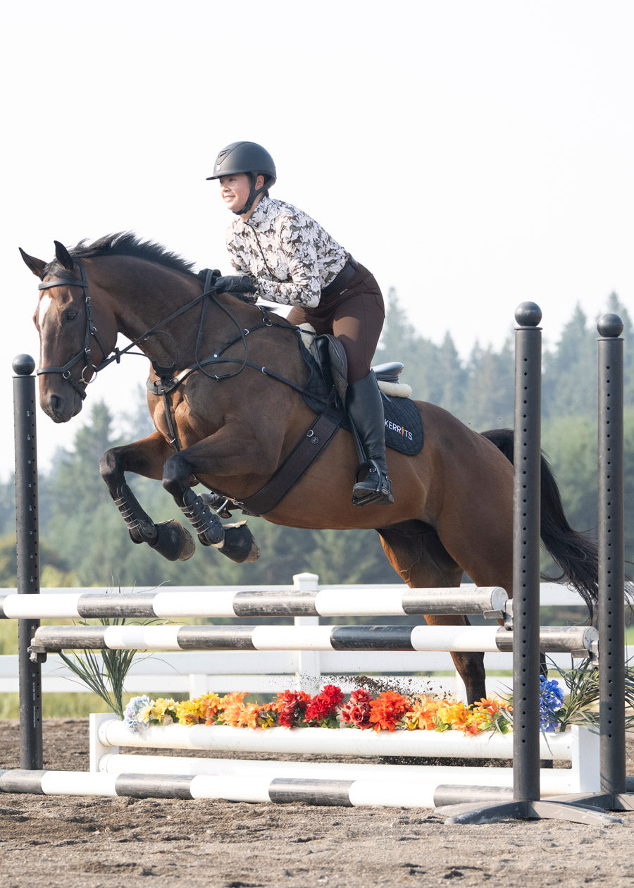 Rider wearing the Kerrits K-Flex™ Knee Patch Breech mid-jump, emphasizing stability and stretch.