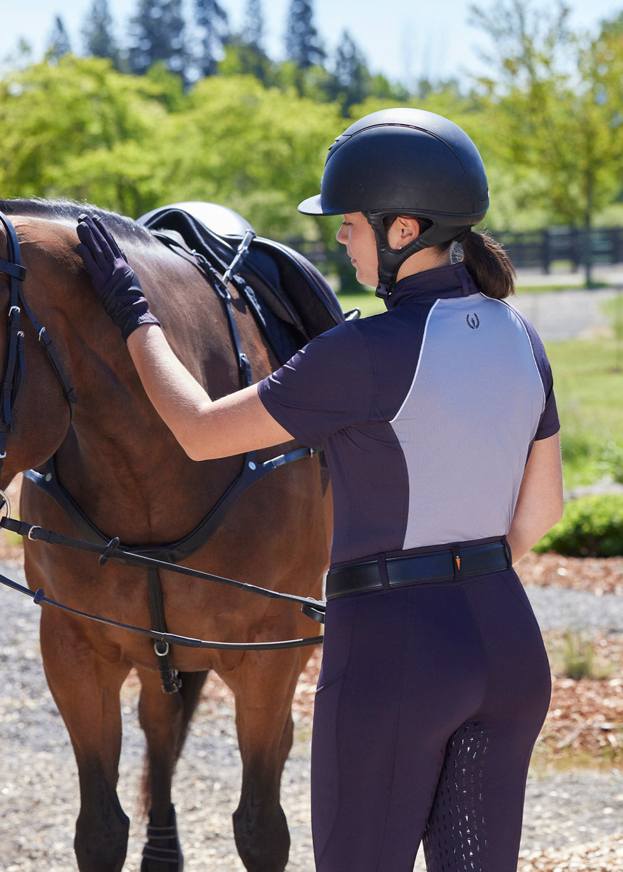 Equestrian relaxing after a summer ride in the Charisma Coolcore Short Sleeve Riding Shirt, paired with riding tights for a polished and functional look.