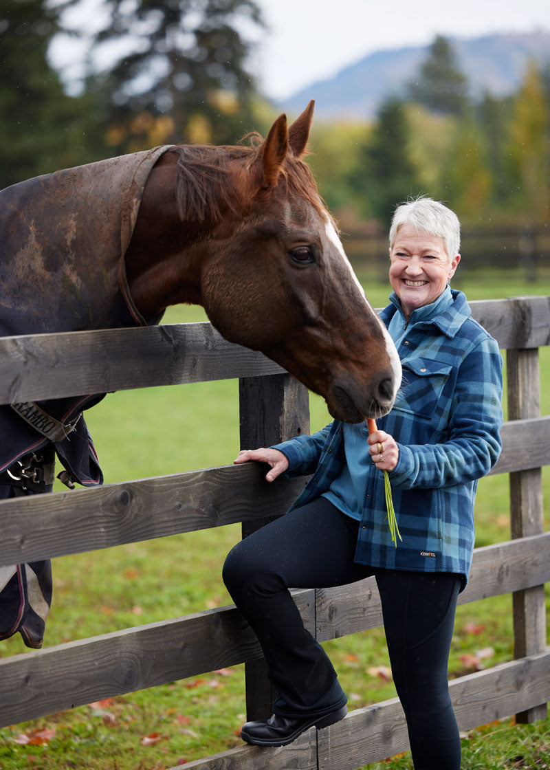 Individual feeding a horse in the bootcut pants, highlighting their durability and practicality for everyday equestrian activities