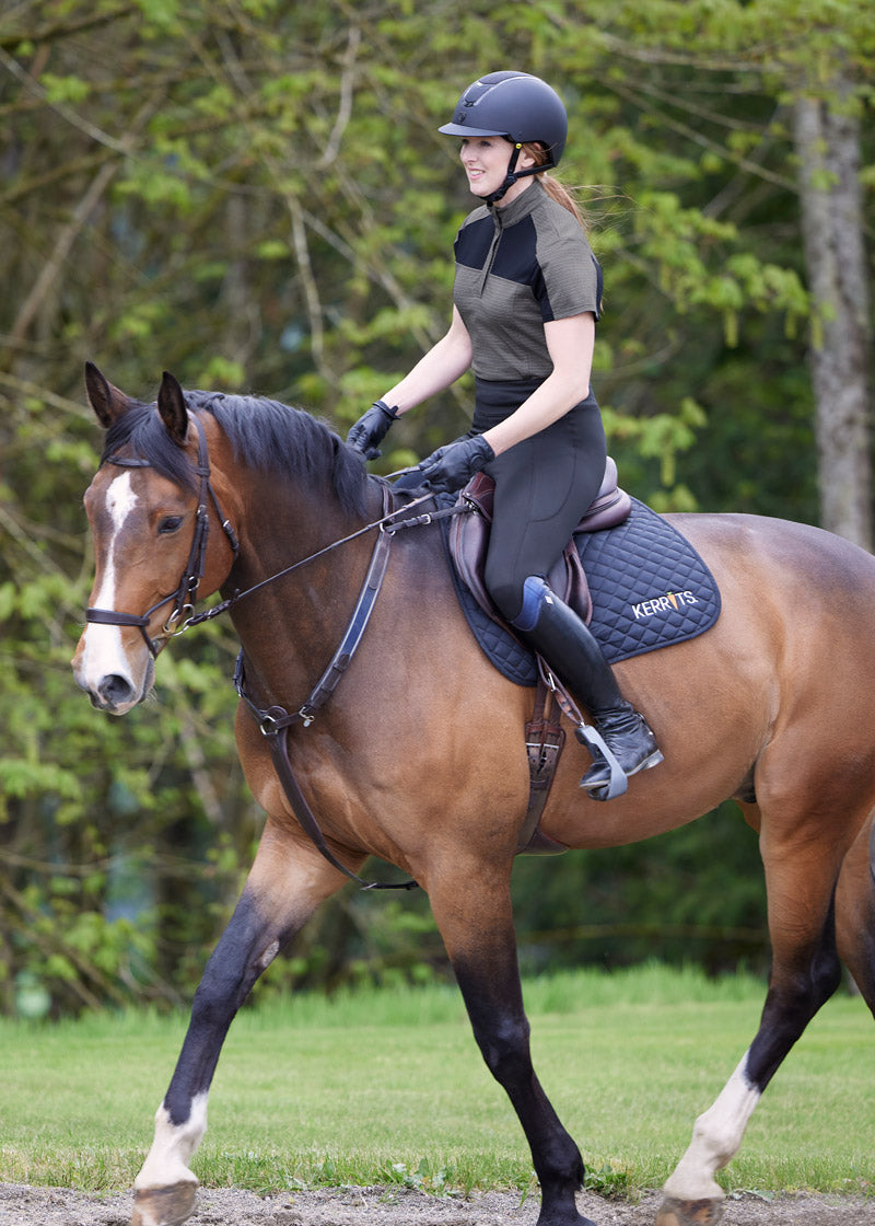 Equestrian sporting the Free Style Knee Patch Pocket Tight during an outdoor ride, highlighting the tights' performance in natural conditions.
