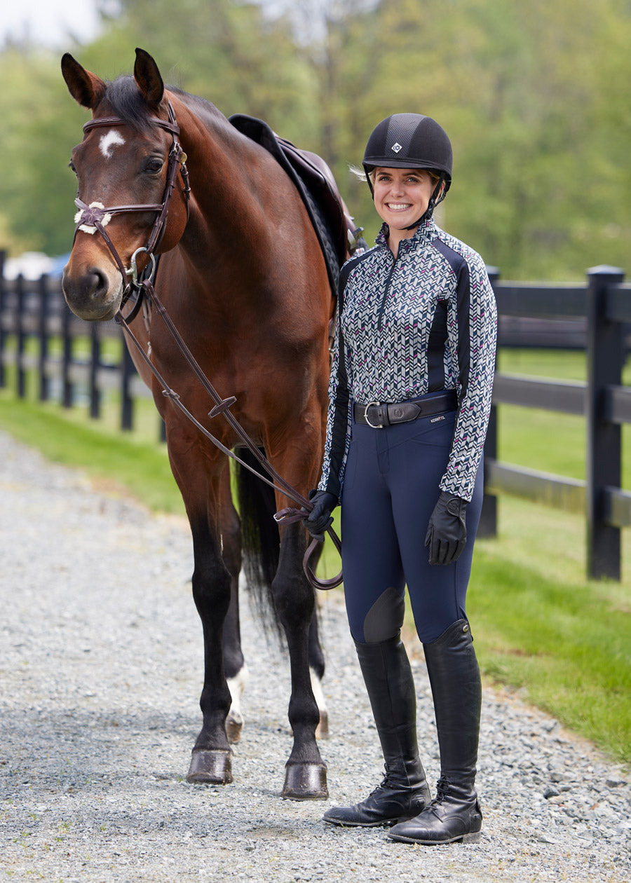 Equestrian wearing Crossover II Knee Patch Breech in Navy, standing next to her horse after a ride.