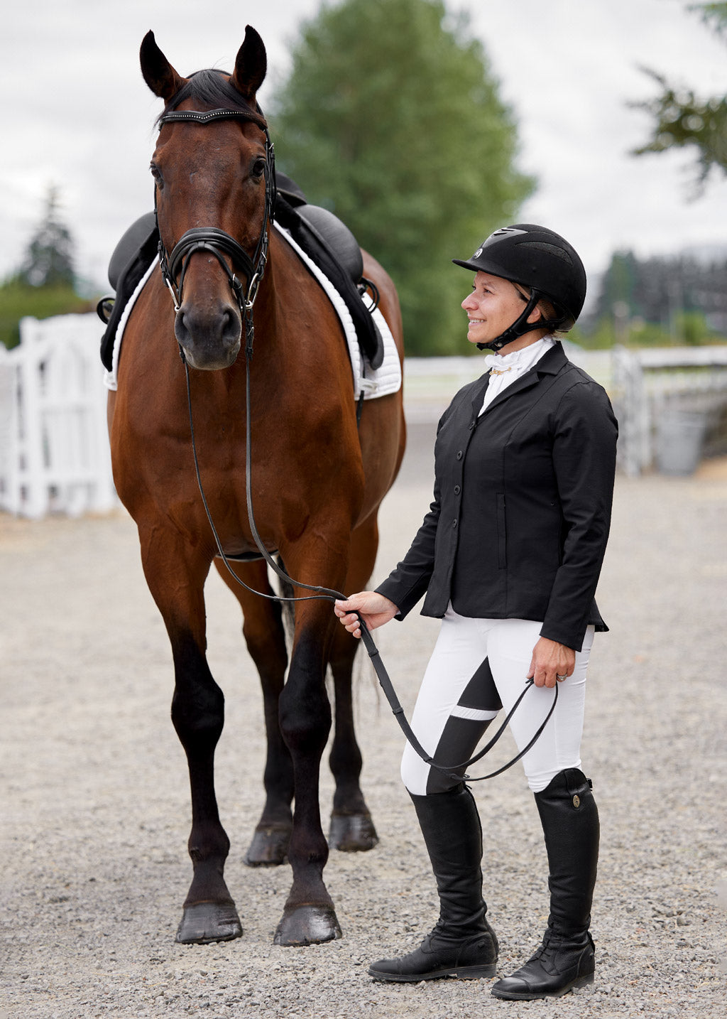 Rider wearing the Crossover II Full Seat Breech in white, standing next to horse after a competition.