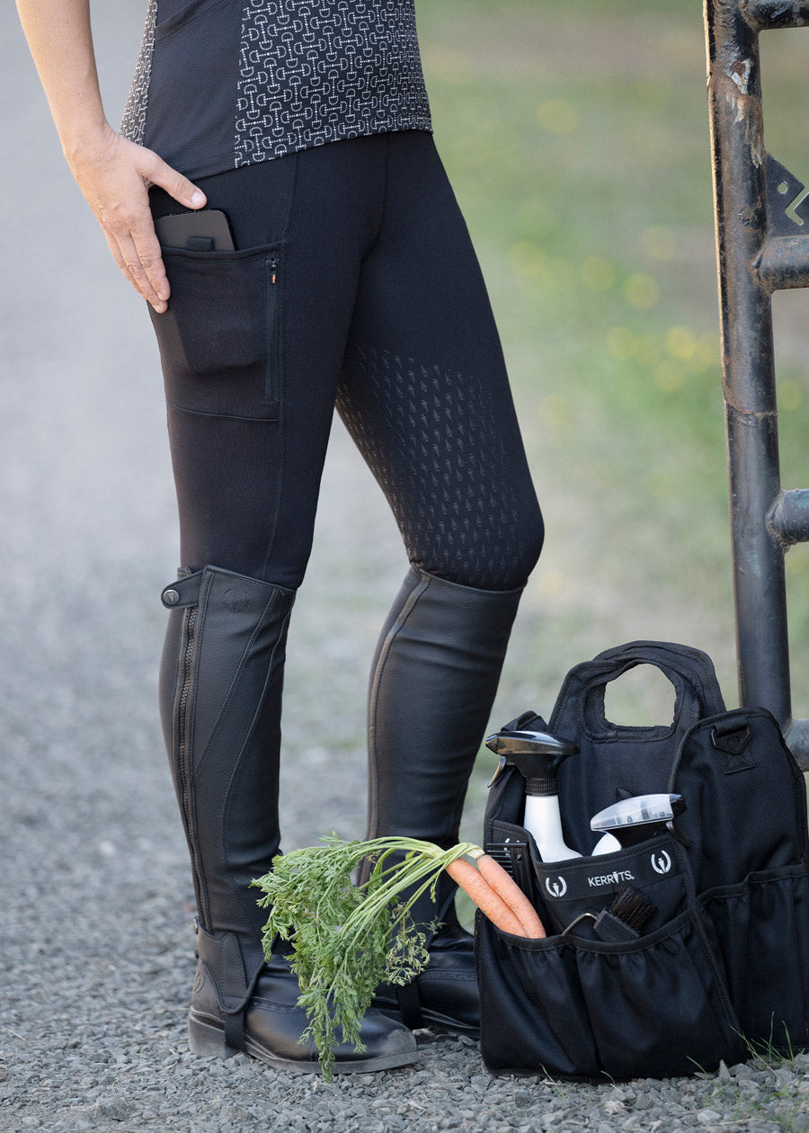 Side profile of a model wearing the Solutions Full Leg Pocket Utility Riding Tight in Black, showcasing the side pockets and sleek fit.
