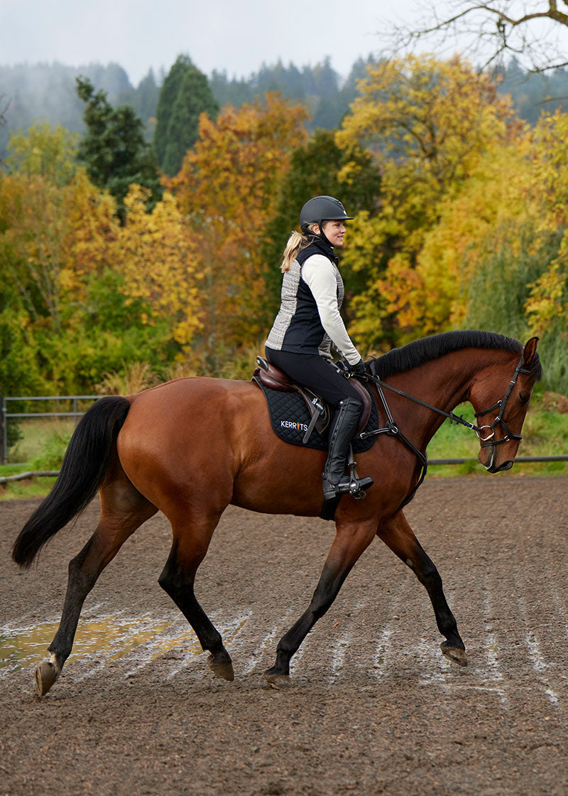 Equestrian wearing the Microcord™ Knee Patch Pocket Tight under an insulated riding jacket, illustrating a layering option for cooler temperatures.