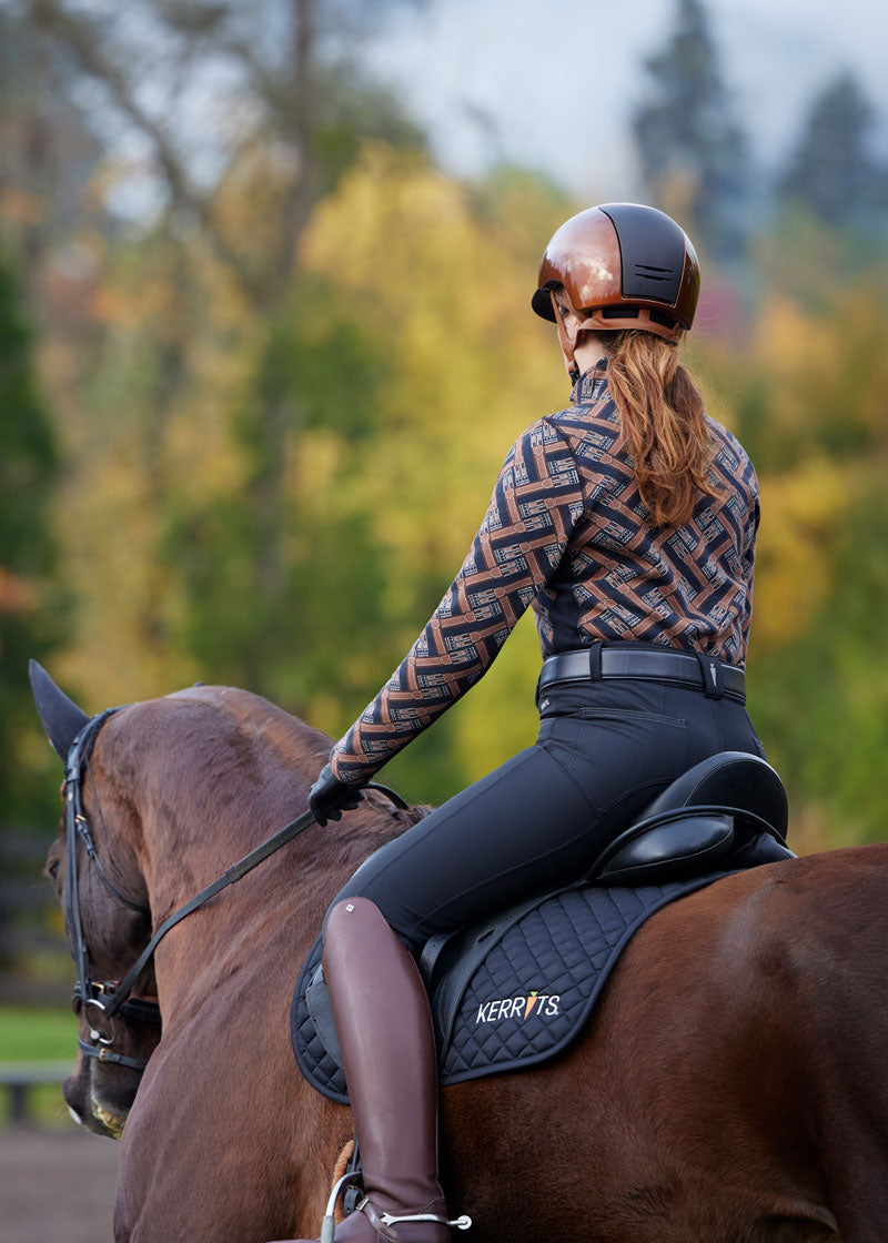 Rider wearing the Kerrits K-Flex™ Knee Patch Breech while schooling in the arena, showcasing the knee patch grip in action.