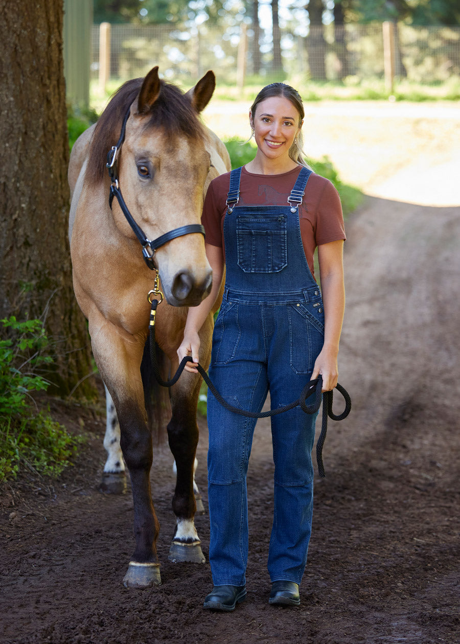 Equestrian wearing the overalls while holding a horse, demonstrating their practicality and comfort