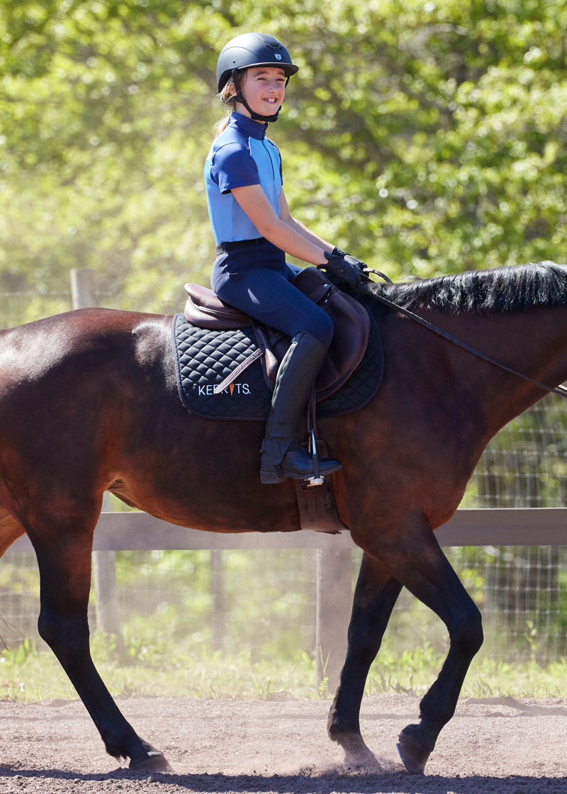 Young rider wearing the Coolcore® Silicone Full Leg Riding Tech Tight while riding, demonstrating the functional design and comfortable fit