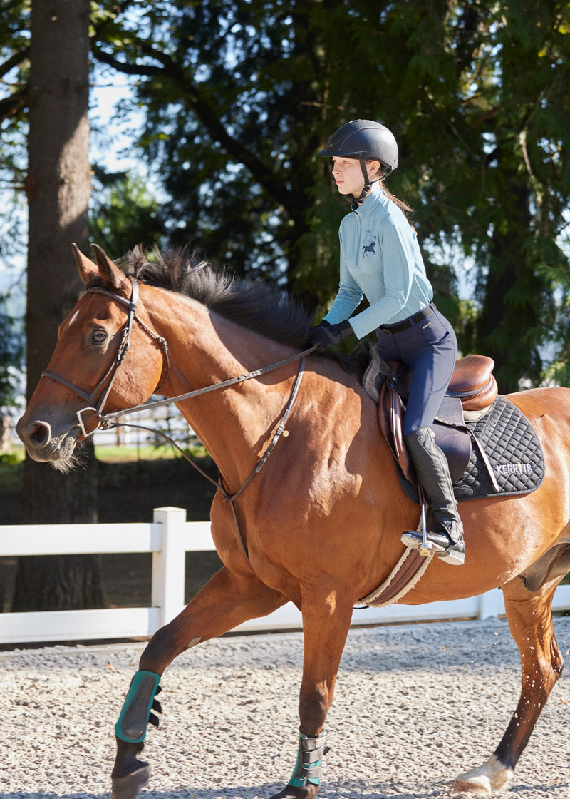 Young rider wearing the Coolcore® Silicone Full Leg Riding Tech Tight while riding, demonstrating the functional design and comfortable fit