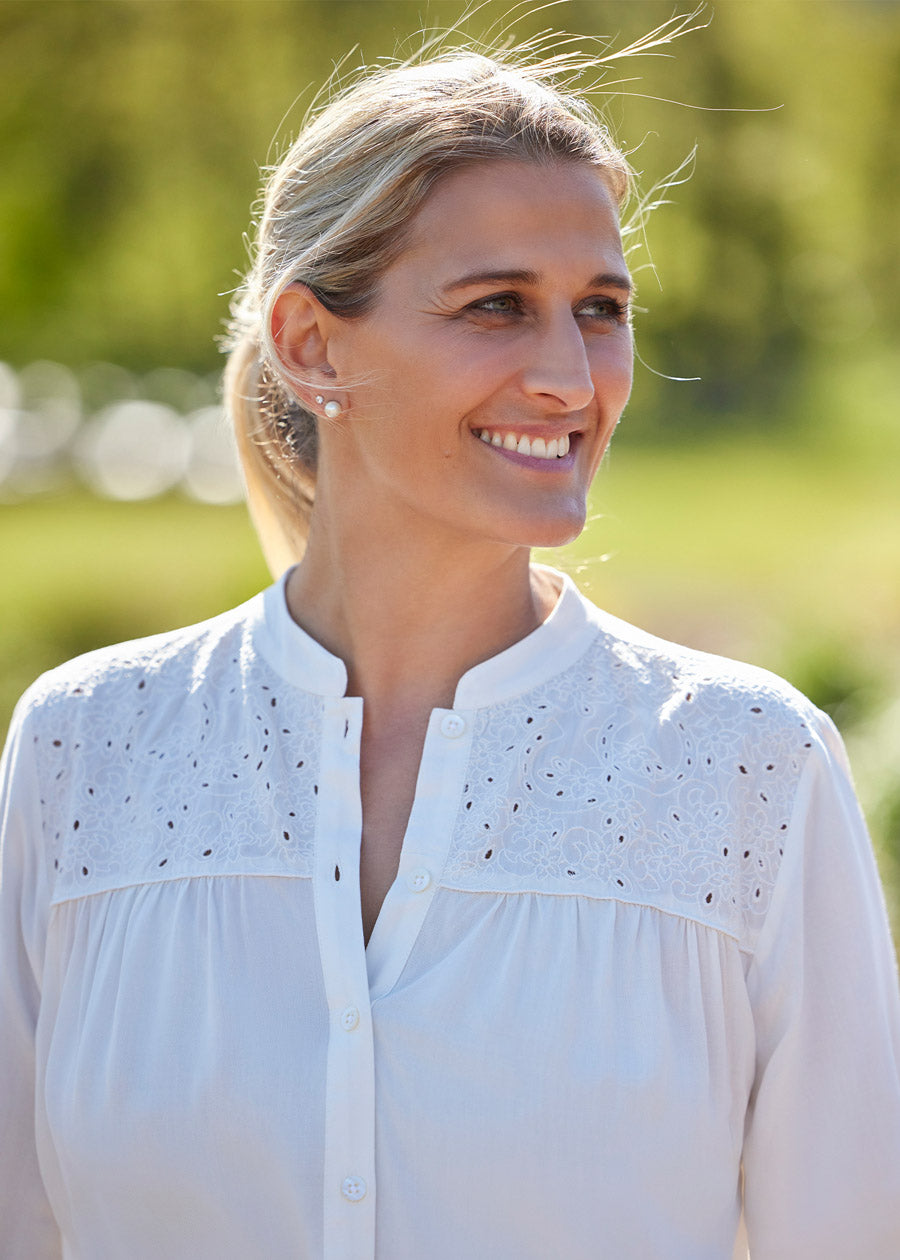 Close-up of the Kerrits Hollyhocks & Horseshoes Blouse on a model, focusing on the floral horseshoe cutout embroidery on the front yoke.