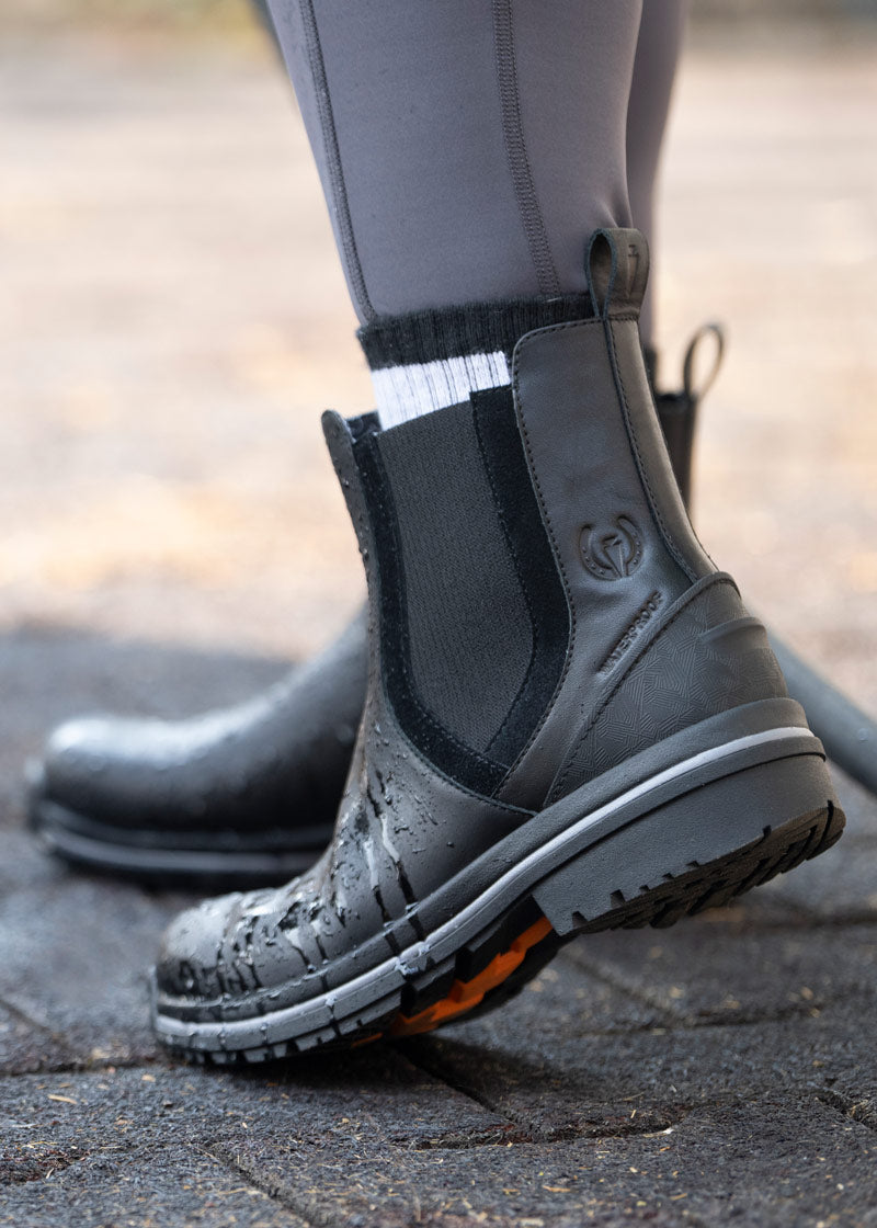 Close-up of the Coachella Pull On Waterproof Barn Boot in black worn while washing horse, featuring the waterproof technology.