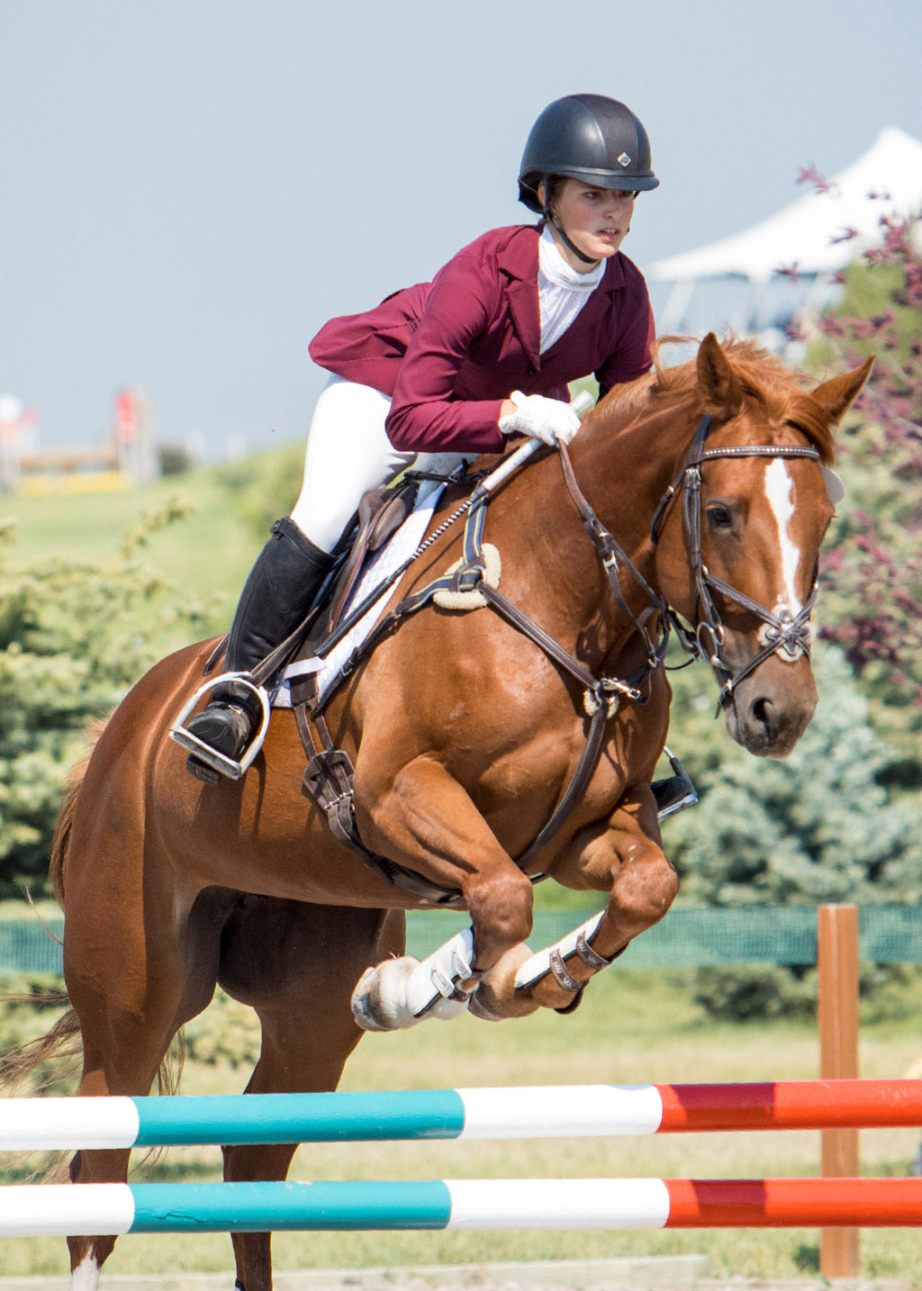 Competitor riding outdoors while wearing the Crossover II® Knee Patch Riding Breech in white, illustrating the breech’s lightweight, breathable fabric in action.