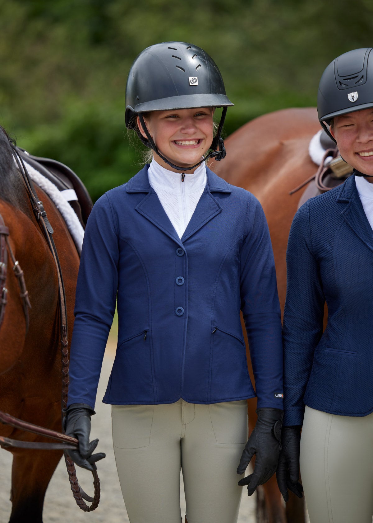 Rider standing beside a horse, dressed in the Crossover II® Knee Patch Breech, highlighting the stylish and functional design suitable for competitions