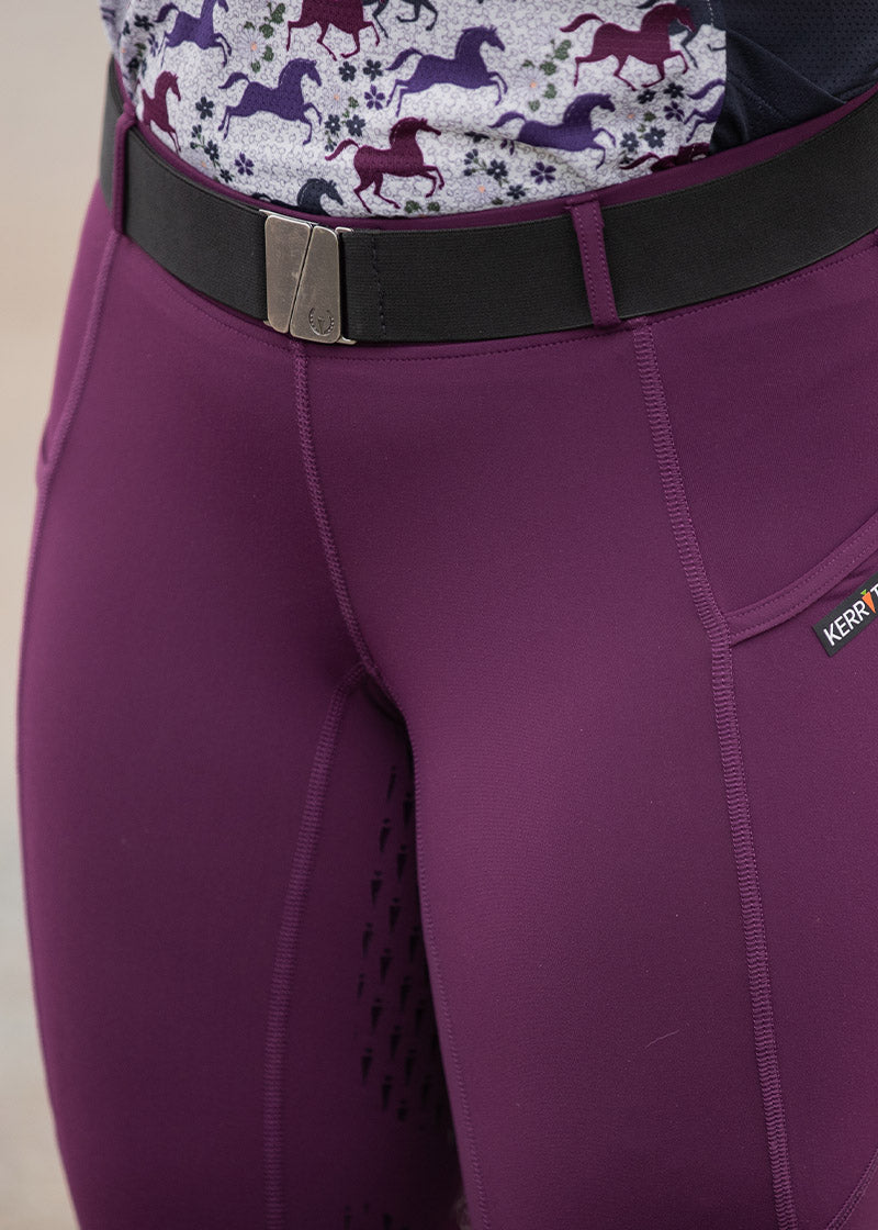 Close-up of the rider's waist area, highlighting the belt's design and the Kerrits logo on the buckle