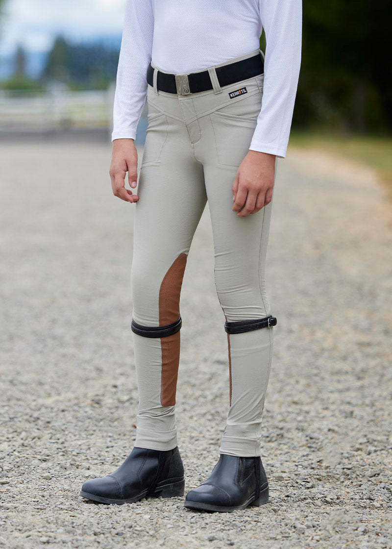 Close-up of the rider's leg, showcasing the extended knee patch providing grip from knee to ankle