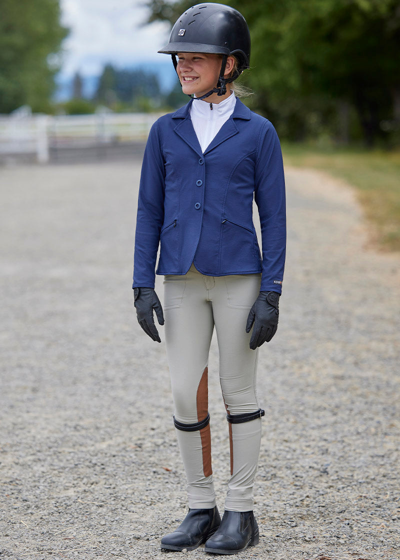 Rider standing dressed in the Crossover™ Extended Knee Patch Jodhpurs, highlighting the stylish and functional design suitable for competitions