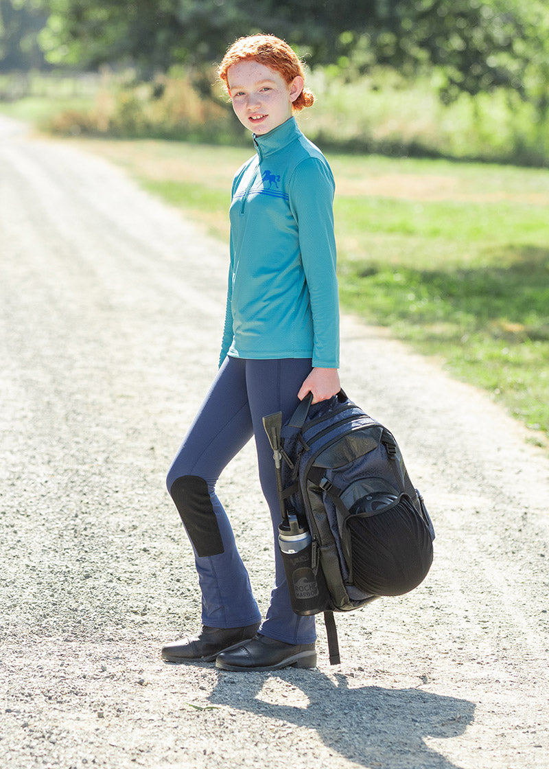 Rider holding a fully packed Kerrits EQ Backpack in Navy, illustrating its practicality for barn use.