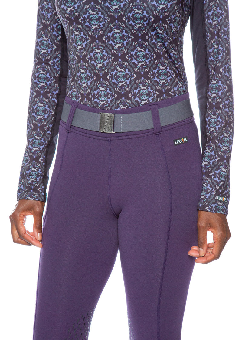 Close-up of the rider's waist area, highlighting the belt's design and the Kerrits logo on the buckle