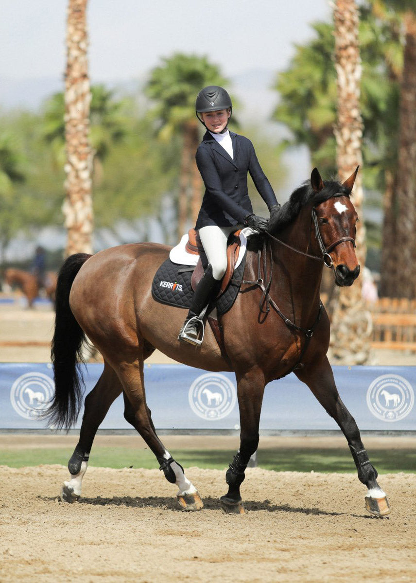 Young rider wearing the Affinity Aero Show Coat during a competition, demonstrating the coat's fit and breathability in action