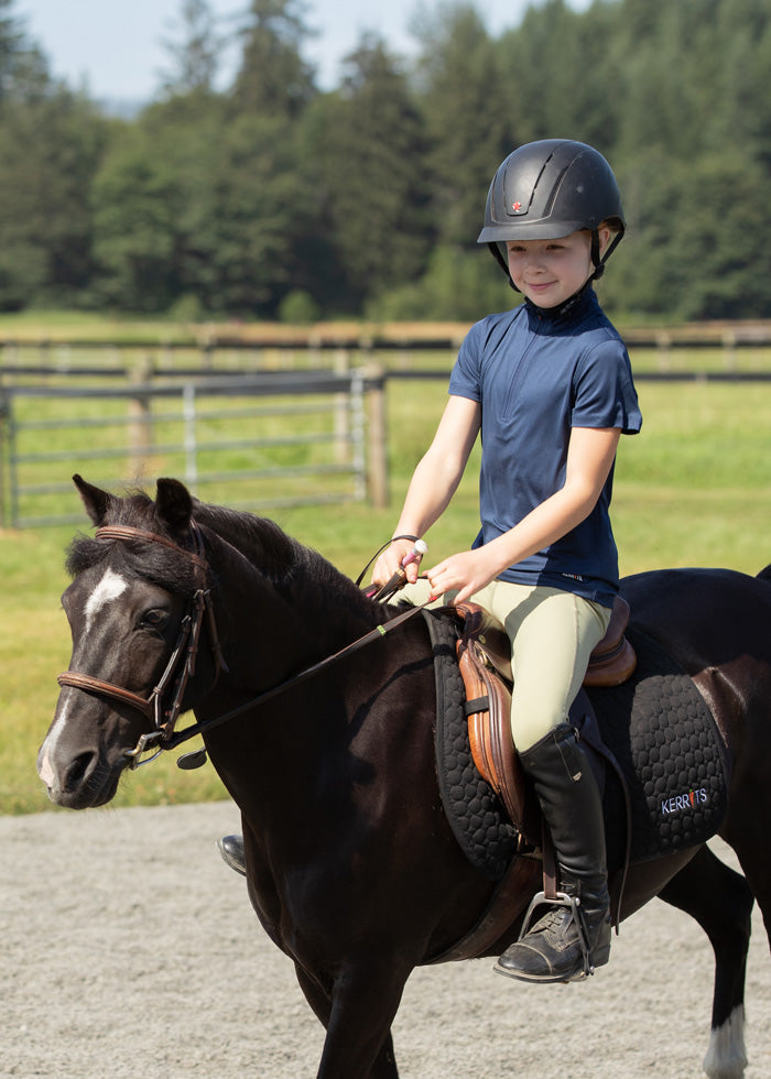 Young rider wearing the Ice Fil® Lite Short Sleeve Riding Shirt during a lesson, demonstrating comfort and flexibility