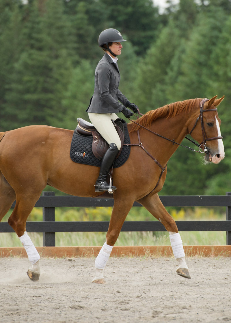 Equestrian wearing the Stretch Competitor Koat while riding, demonstrating the coat's flexibility and elegant appearance in the saddle