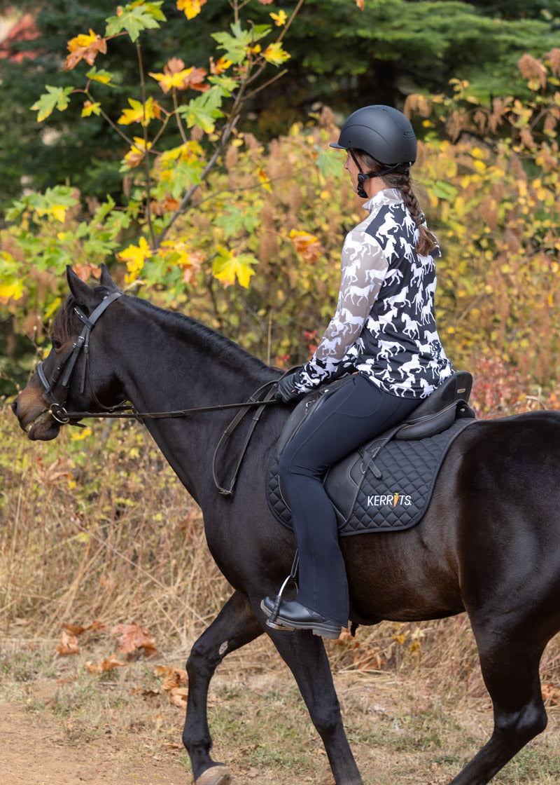 Equestrian riding her horse in the Coolcore® Full Leg Bootcut Riding Tight - Tall in Black, highlighting the bootcut hem in saddle.