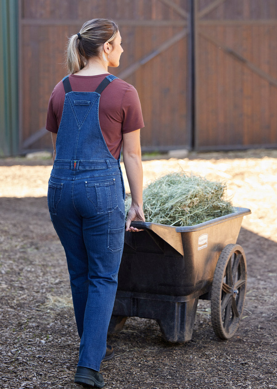 Individual wearing the overalls in a stable setting, illustrating their suitability for barn chores