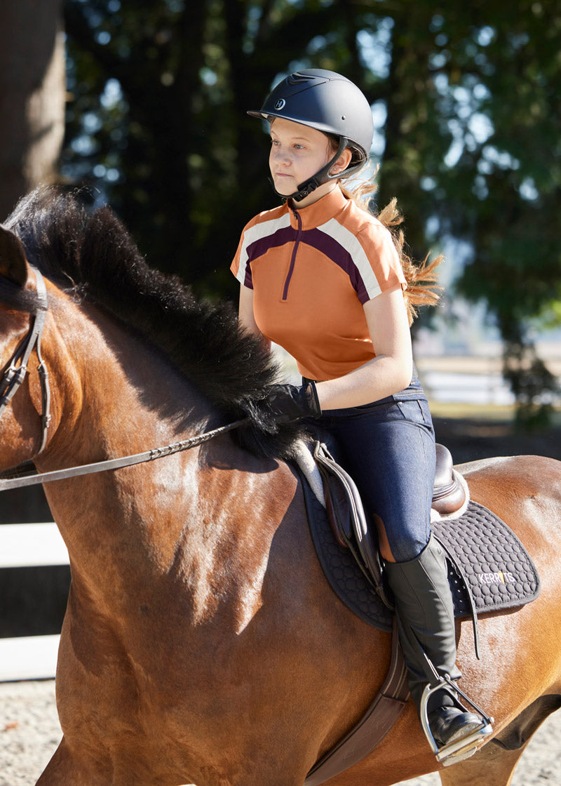 Young rider wearing the breech during a riding session, demonstrating the comfort and flexibility provided by the stretch denim and knee patches