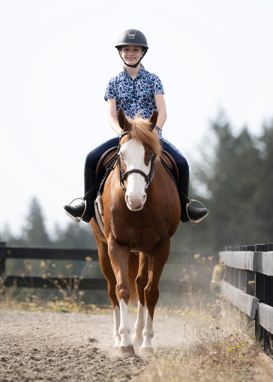 Young rider wearing the Breeze Ice Fil® Short Sleeve Riding Shirt while riding, demonstrating the shirt's breathability and comfortable fit
