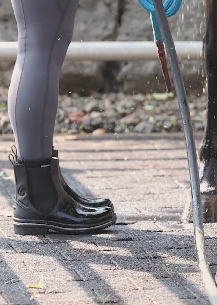 Video of rider wearing the Coachella Barn Boot at the barn while washing their horse, highlighting the waterproofing of this boot.